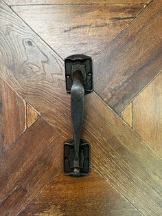 a door handle on the side of a wooden door with wood flooring in the background