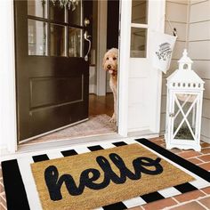 a door mat with the word hello written on it and a dog peeking out from behind