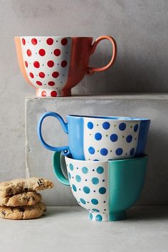 three cups and two cookies are stacked on top of each other in front of the wall