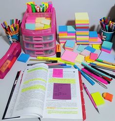 an open book sitting on top of a table filled with assorted colored paper and markers