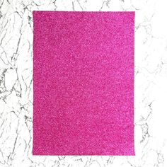 a pink piece of paper sitting on top of a marble countertop next to a white wall