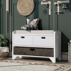 a white dresser with baskets on it in front of a green wall and some plants