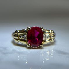 Beautiful red gemstone and diamond ring in a vintage like style and intricate gold band detailing. One large oval cut synthetic ruby centre stone, prong set. Two small pave set diamonds on each side of the centre ruby.  Pre-loved item. Stamped 14KT yellow gold.  Ring Size 9.25 US Weight: 5.110g **FREE shipping within Canada and USA** If you have any questions or concerns, please do not hesitate to contact us. We will be more than happy to help you and answer any inquiries.  We invite you to chec Formal Oval Ruby Ring With Center Stone, Oval Ruby Ring With Prong Setting, Oval Ruby Ring Fine Jewelry, Red Diamond Oval Cabochon Ring, Oval Ruby Ring With Gemstone Accents In Yellow Gold, Oval Ruby Diamond Ring, Formal Oval Lab-created Ruby Ring, Formal Ruby Ring With Oval Cabochon And Accent Stones, Classic Rings With Oval Cabochon Gemstone Accents