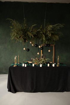 a table with candles, greenery and ornaments hanging from it's centerpieces