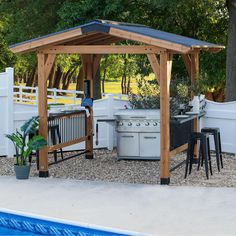 a gazebo next to a swimming pool with an outdoor kitchen and grill area in the background