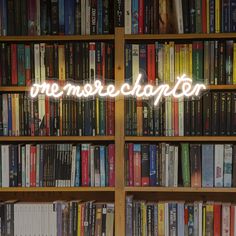 a book shelf filled with lots of books next to a neon sign that reads,'we miss you teacher '