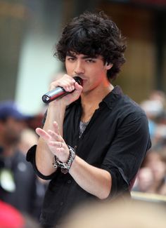 a young man holding a microphone in front of his face as he sings into the crowd