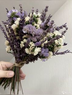 a person holding a bunch of flowers in their hand with purple and white blooms on it