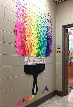 a welcome sign with hearts on it in front of a rainbow painted wall and door