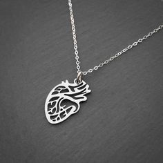 a silver necklace with a heart and lungs in the shape of a human head on a chain