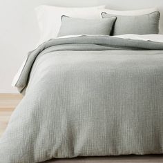 a bed with two pillows on top of it next to a white wall and wooden floor