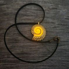 a necklace with a yellow sunflower on it sitting on top of a wooden table