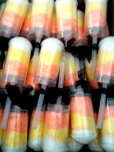 there are many orange and yellow candy sticks in plastic containers with black bows on them