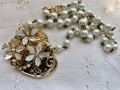 Offering a gorgeous gold necklace made from two repurposed vintage white Mother of Pearl earrings, a matching Mother of Pearl brooch and additional gold filigree rounds. An educated guess dates this centerpiece from as far back as 1960's. Just look at the style - definitely not made like this anymore! I attached a white pearl rosary chain. The necklace is a total of 19 inches in length - the chain alone is 17.5 inches and the centerpiece itself is 2 inches by 2.25 inches wide. Please remember th Ornate Antique Gold Necklace For Weddings, Vintage Bridal Necklace With Intricate Design For Gift, Vintage Bridal Necklace With Intricate Design As Gift, Vintage Bridal Necklace With Intricate Design For Wedding, White Heirloom Necklace For Wedding, Heirloom White Necklace For Wedding, Victorian White Wedding Necklaces, White Victorian Wedding Necklaces, Heirloom White Wedding Necklaces