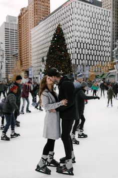 a man and woman are kissing in front of a christmas tree on an ice rink