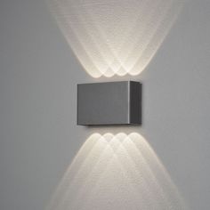 a wall light with two lights on it in the corner of a white walled room