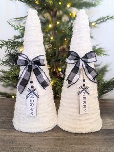 two white christmas trees with black bows and tags on them sitting in front of a tree