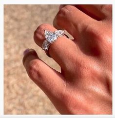 a person's hand with a diamond ring on top of their finger and the other hand holding an engagement ring