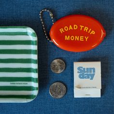 the road trip money is sitting next to a plastic coin case and keychain