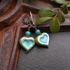 "These cute heart earrings feature a pair of rustic Czech glass beads - the underlying color is chartreuse green with a blue metallic finish. Above sit faceted turquoise blue Czech glass beads and antiqued copper accents. I finished these little beauties with rustic copper plated lever back wires. I can change them out for hook style wires if you prefer. These make a great gift or a sweet treat for yourself!  Earring Length: about 1 1/2\" including wire Your earrings will arrive in an eco-friendly Kraft paper gift box. Heart Collection https://www.etsy.com/shop/BonArtsStudio?ref=hdr_shop_menu&section_id=25986424 More Beaded Beauties https://www.etsy.com/shop/BonArtsStudio?ref=hdr_shop_menu&section_id=17052813 See What's New https://www.etsy.com/shop/BonArtsStudio?ref=hdr_shop_menu&section_ Turquoise Heart Earrings, Unique Valentines Gifts, Turquoise Boho, Turquoise Heart, Unique Valentines, Valentines Gifts For Her, Victorian Jewelry, Glass Heart, Czech Beads