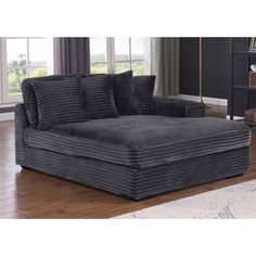 a large gray couch sitting on top of a hard wood floor next to a window