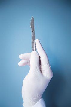 a person in white gloves holding up a small toothbrush