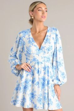 Bring a touch of charm and playfulness to your wardrobe with our Glimmer Of Hope White & Blue Floral Mini Dress. This gorgeous dress features a flattering fit and eye-catching blue floral design, perfect for any occasion. Add a touch of whimsy to your style and feel confident in this stunning mini dress! This dress features a deep v-neckline, ruching in the bust, a fitted waistband, a smocked back insert, and elastic cuffed long sleeves.      100% Linen  Hand Wash Cold  Lined 100% Polyester  Imported  Model is wearing a size small Blue Floral Mini Dress, Glimmer Of Hope, Sorority Rush Dresses, Blue Floral Design, Rush Dresses, Cardigan Crop Top, Little White Dresses, Floral Mini Dress, Event Dresses