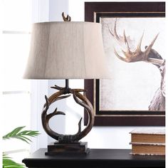 a table lamp with a deer head on it next to a framed photograph and books