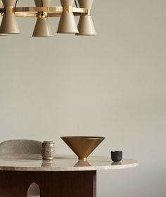 a dining room table with a bowl on it and several lights hanging from the ceiling