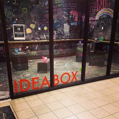 the inside of a store with chalk writing on the walls and an open box sitting in front of it