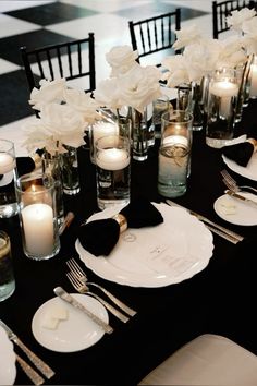 a black table topped with white flowers and candles