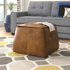 a living room with a couch, chair and ottoman on the floor in front of a window