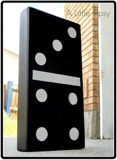 a black block with white dots on it sitting in front of a brick wall and building