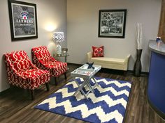 a living room with two red chairs and a blue rug in front of the couch