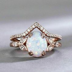 a white opal and diamond ring on a gray surface with the center stone surrounded by diamonds