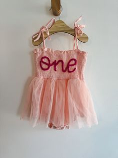 Hand-embroidered "One" first birthday dress / romper! Light pink dress with dark pink lettering. Wash on cold and lay flat to dry. PERFECT for 1st birthday photos or smash cake! *This is a 12 month size dress!* Pink Cotton Dress For First Birthday, Pink Sleeveless Dress For First Birthday, Pink Fitted Cotton Tutu Dress, Pink Cotton Tutu Dress With Ruffles, Pink Tutu Dress For First Birthday In Summer, Pink Sleeveless Tutu Dress For Playtime, Sleeveless Pink Tutu Dress For Playtime, Sleeveless Pink Tutu Dress For Birthday, Sweet Pink Tutu Dress For Birthday