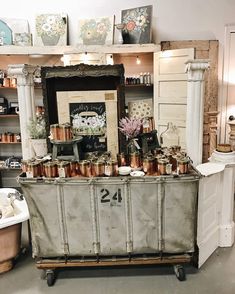 an old metal cart with lots of copper pots on it's sides and some framed pictures above the top