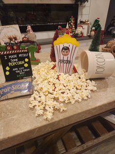 popcorn spilled out of a paper cup on a table with christmas decorations in the background