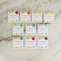 six cards with different colored buttons on them sitting on a marble surface next to scissors