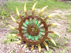 a metal sunflower sitting on top of a grass covered field