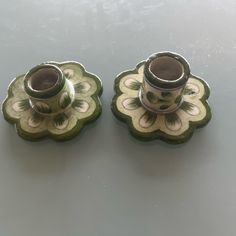 two green and white vases sitting on top of a table