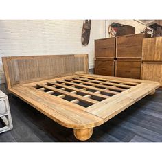 a bed frame made out of wood with drawers in the background