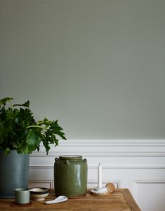 a potted plant sitting on top of a wooden table next to two cups and spoons