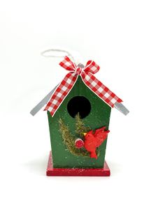 a green birdhouse with a red and white checkered bow