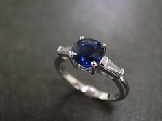 a blue ring with three baguets on it sitting on top of a table