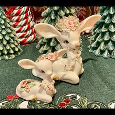 two ceramic rabbits sitting next to each other in front of christmas trees and candy canes