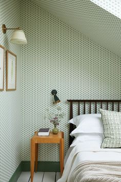 a bedroom with green wallpaper and white bedding