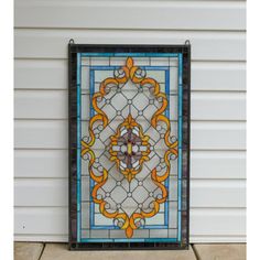 a decorative stained glass window on the side of a white house with an orange and blue design