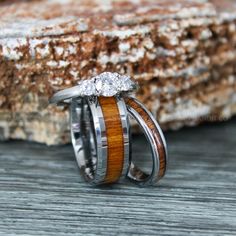 two wedding rings with wood and diamonds on them