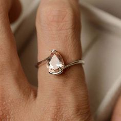 a woman's hand wearing a ring with an oval shaped morganite stone on it